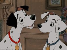 two dalmatian dogs standing next to each other in front of a fireplace with flowers