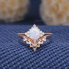 an opal and diamond ring sits on a blue blanket