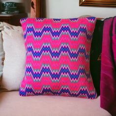 a pink and blue pillow sitting on top of a couch