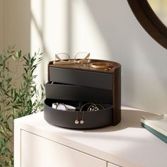 a pair of glasses sitting on top of a wooden box next to a plant and mirror