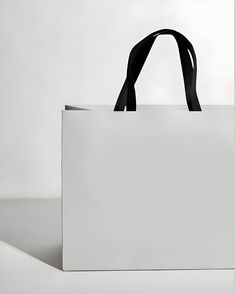 a white bag sitting on top of a table next to a black handle and strap