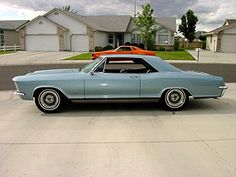 an old blue car parked in front of a house