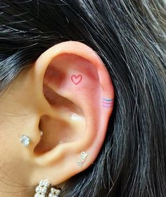 a woman's ear with a small heart tattoo on the middle of her left ear