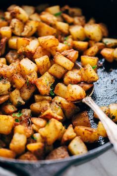 cooked potatoes in a pan with a wooden spoon