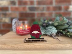 a small wooden bird sitting on top of a piece of wood next to a candle