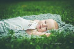 a baby laying in the grass with his eyes closed and looking up at the camera