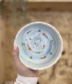 a hand holding a bowl with fish in it