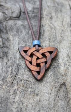 a wooden necklace with an intricate knot on it's end sitting on a rock