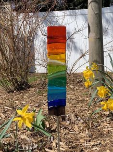 there is a multicolored piece of glass on the ground next to some daffodils