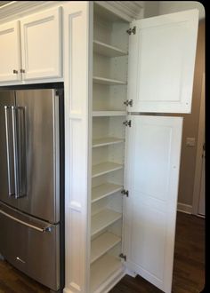 an empty pantry in the middle of a kitchen with white cabinets and stainless steel appliances