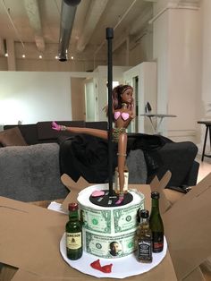 a barbie doll standing on top of a cake with money and wine bottles around it