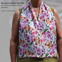 a woman standing in front of a white wall wearing a flowered scarf over her shoulders