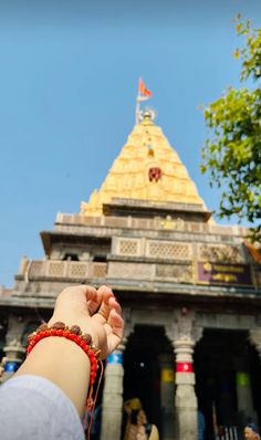 a person holding their hand out in front of a building with a gold dome on top