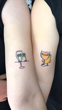 two people with tattoos on their arms holding wine glasses and a glass in the other hand