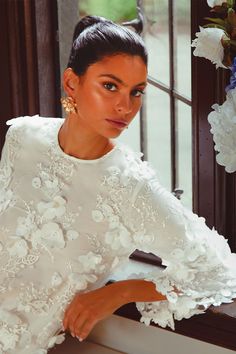 a woman sitting on a window sill with flowers in the background