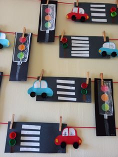 paper cars and traffic lights are hanging on the clothes pins in front of a wall