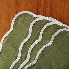 three pieces of green fabric with white trims on a wooden surface, one folded and the other unwrapped