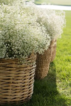 three baskets filled with white flowers sitting in the grass