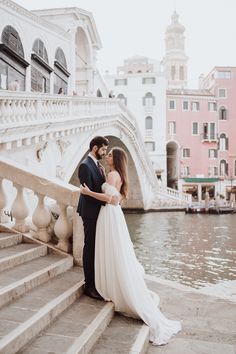 a bride and groom are standing on the steps by the water in venice, italy