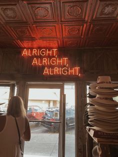 a woman standing in front of a store window with the words alright, alright on it