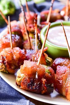 several skewered food items on a plate with dipping sauce