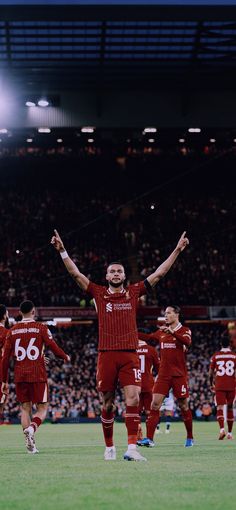 a group of men standing on top of a soccer field holding hands in the air