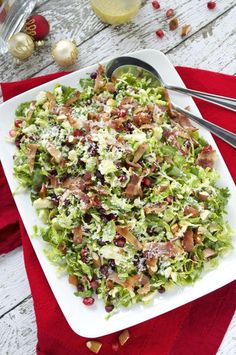 a white plate topped with a salad covered in lettuce and bacon next to silverware