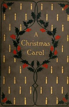 a christmas carol book with holly leaves and red berries on the cover, surrounded by candles