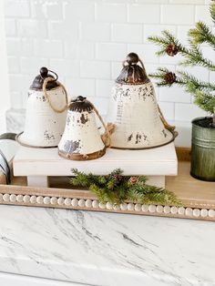 three bells are sitting on a tray next to a christmas tree