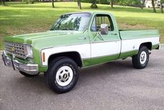 a green and white pick up truck parked in a parking lot