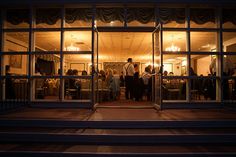 people are standing in the doorway of a restaurant at night