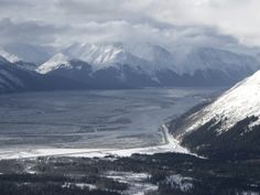 the mountains are covered in snow and clouds as seen from an overcast day,