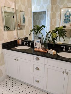 a bathroom with two sinks, mirrors and plants in the corner on the counter top