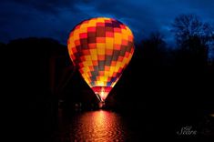 a colorful hot air balloon flying over water at night