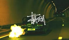 a car driving through a tunnel with graffiti on it's side and fire coming out of the back