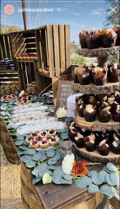 a table topped with lots of cakes and cupcakes on top of wooden crates