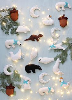 christmas ornaments are arranged on a table with string lights and pine cones in the shape of animals