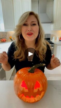 a woman sitting at a table with a pumpkin in front of her