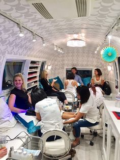 a group of people sitting around in a room with mirrors and lights on the ceiling