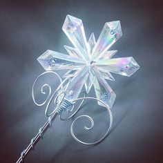 a crystal snowflake with swirls on it's side and a wand in the middle