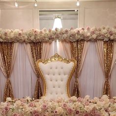 a white chair sitting in front of a window covered in pink and white flowers with gold trim