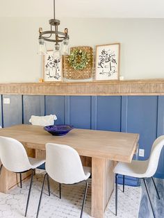 a dining room table and chairs with blue walls in the background, along with artwork on the wall