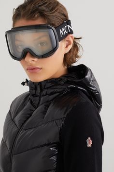 a woman wearing ski goggles and a black jacket with the word mcn on it