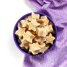 a blue bowl filled with cut up pieces of food on top of a purple and white cloth