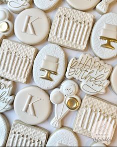 cookies decorated with icing and fondant are arranged on a white tablecloth that says happy birthday