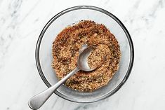 a glass bowl filled with food on top of a white counter next to a spoon