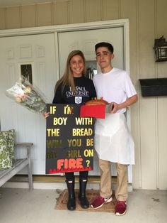 a man and woman standing in front of a door holding a sign that says if boy i'm with the bread will you be my girl on fire?