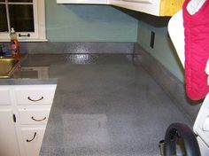 a kitchen with grey counter tops and white cupboards next to a stove top oven