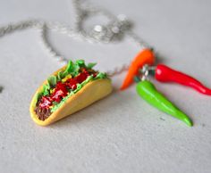 a taco necklace with chili, lettuce and peppers hanging from it's side