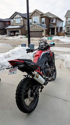 a red and black motorcycle parked in front of some houses